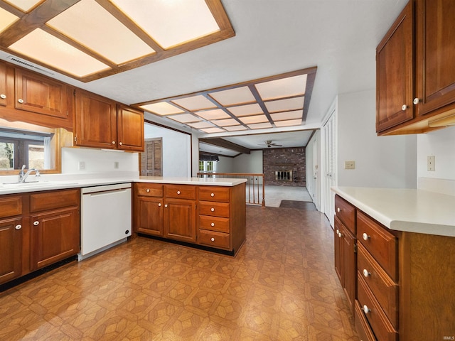 kitchen featuring sink, dishwasher, kitchen peninsula, ceiling fan, and a fireplace