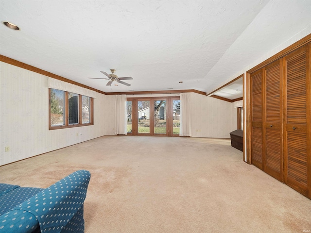 carpeted living room with lofted ceiling, ceiling fan, crown molding, and a textured ceiling