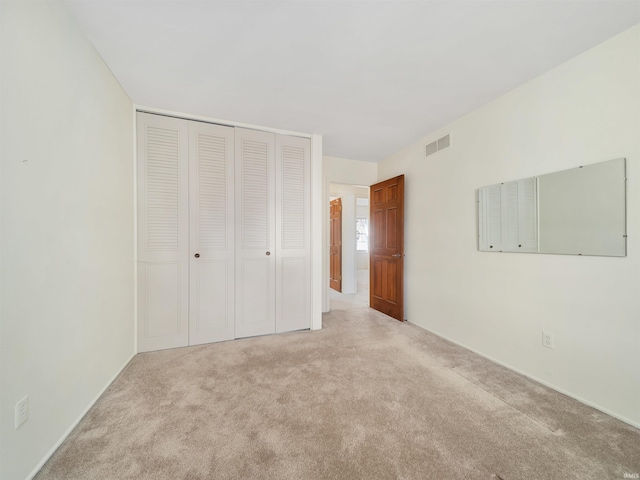 unfurnished bedroom with a closet and light carpet