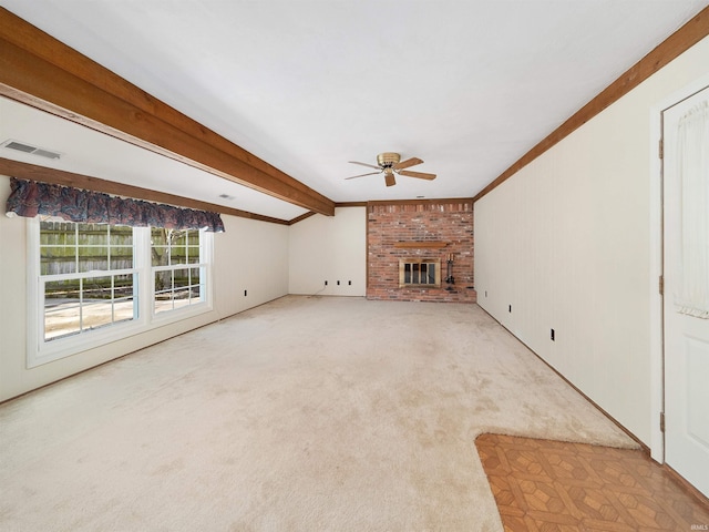 unfurnished living room with beam ceiling, crown molding, ceiling fan, light colored carpet, and a fireplace