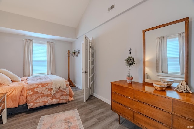 bedroom featuring hardwood / wood-style flooring, lofted ceiling, and multiple windows