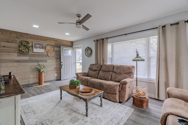 living room featuring wooden walls, ceiling fan, and light wood-type flooring