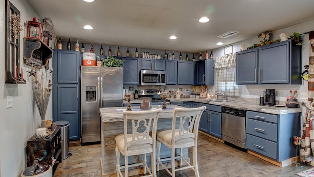 kitchen with blue cabinetry, appliances with stainless steel finishes, light hardwood / wood-style floors, and sink