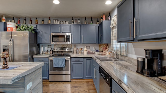 kitchen with stainless steel appliances, sink, and light hardwood / wood-style flooring