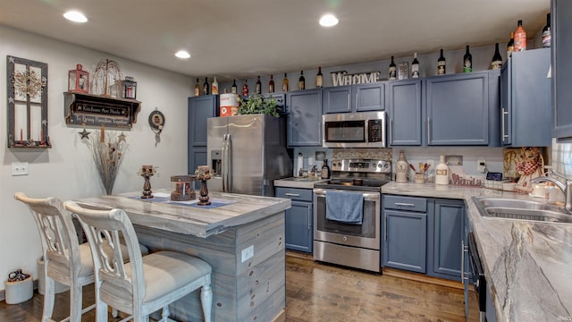 kitchen featuring stainless steel appliances, dark hardwood / wood-style flooring, sink, and blue cabinetry