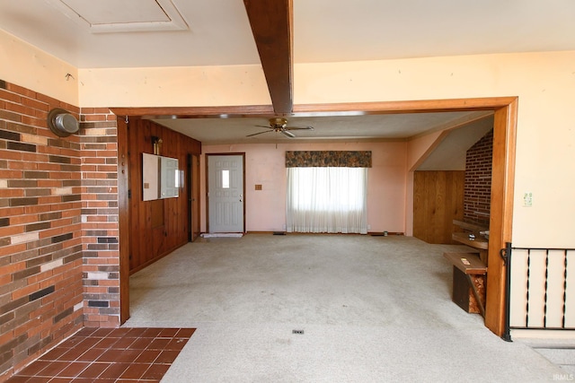 foyer featuring ceiling fan, carpet floors, wooden walls, and beamed ceiling