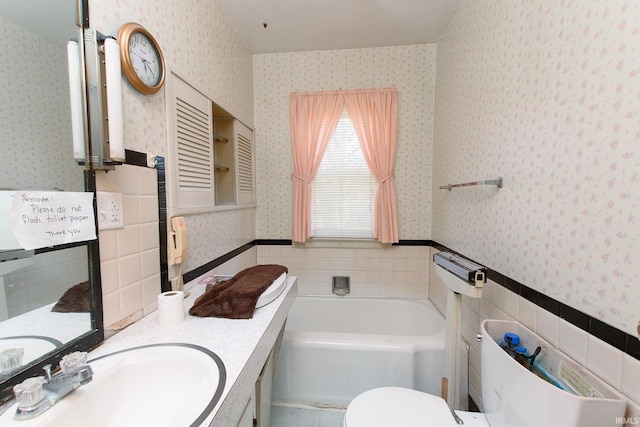 bathroom with vanity, tile walls, a bathtub, and toilet