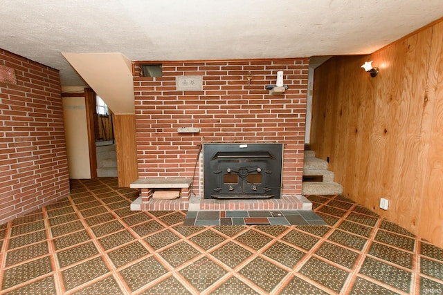 unfurnished living room featuring a wood stove, a textured ceiling, and wooden walls