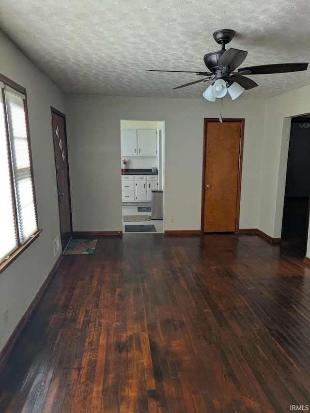 unfurnished living room with ceiling fan, a textured ceiling, and dark hardwood / wood-style flooring