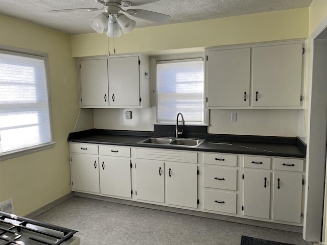 kitchen with white cabinetry, ceiling fan, sink, and a textured ceiling