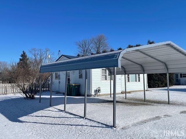 snow covered parking featuring a carport