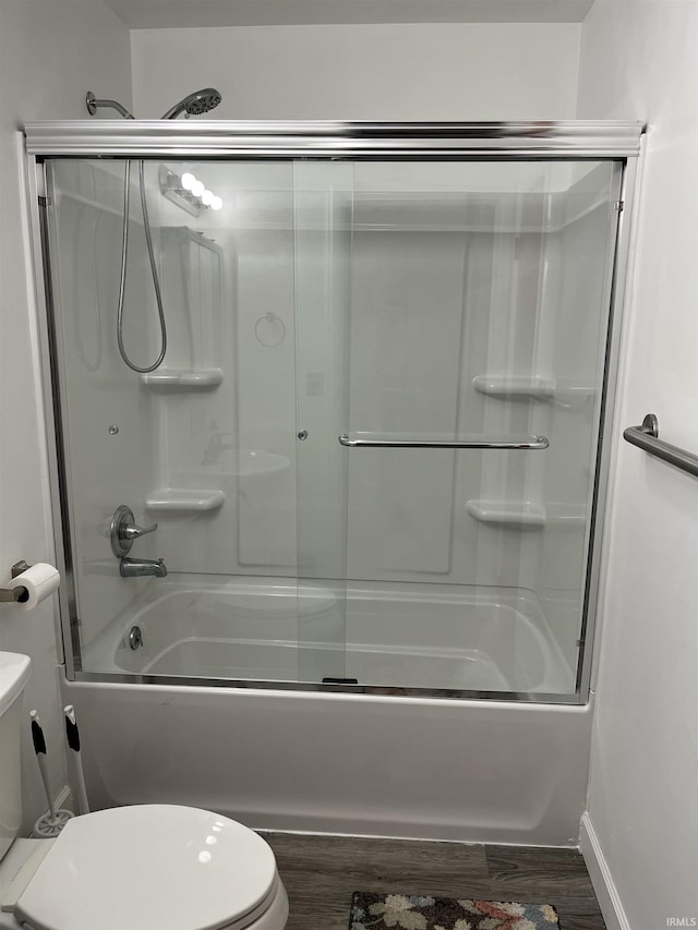 bathroom featuring hardwood / wood-style flooring, shower / bath combination with glass door, and toilet