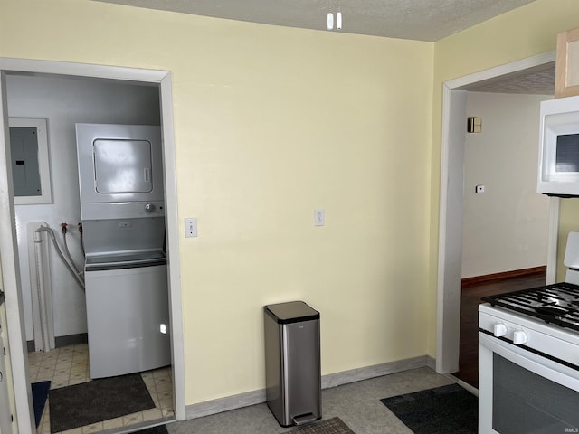 kitchen featuring stacked washer / drying machine, white appliances, and electric panel