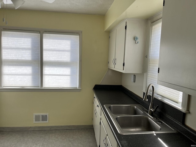 kitchen with sink, a textured ceiling, white cabinets, and ceiling fan