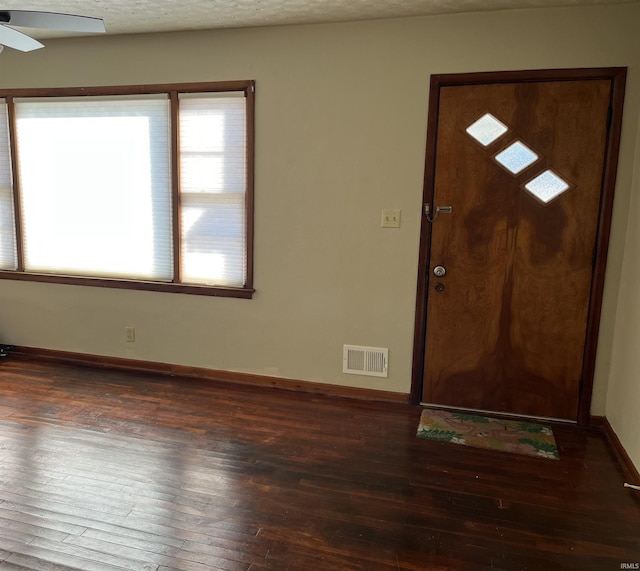 foyer entrance featuring dark wood-type flooring, ceiling fan, and a textured ceiling