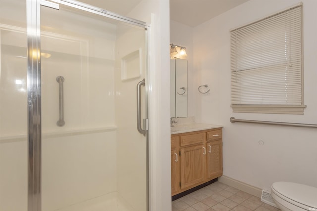 bathroom with vanity, toilet, tile patterned floors, and a shower with shower door