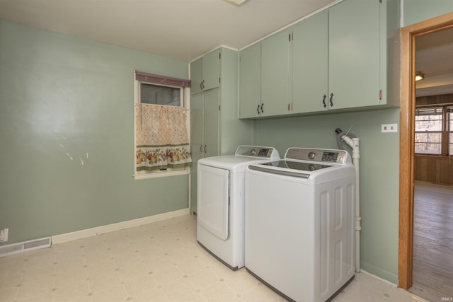 clothes washing area featuring independent washer and dryer and cabinets