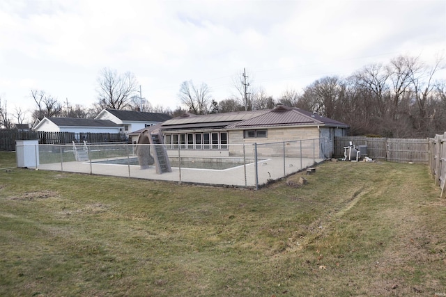 back of house with a covered pool, a lawn, and central air condition unit