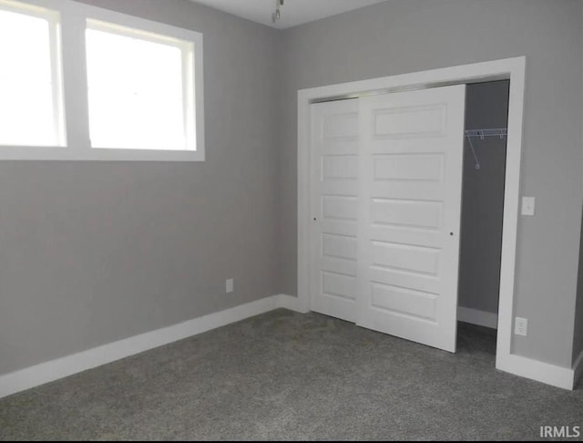 unfurnished bedroom with dark carpet and a closet