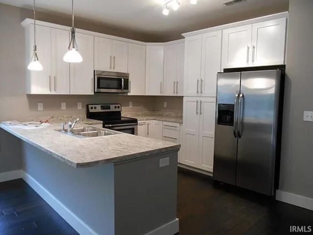 kitchen with hanging light fixtures, white cabinetry, appliances with stainless steel finishes, and kitchen peninsula