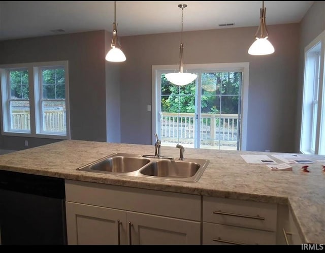 kitchen featuring white cabinetry, black dishwasher, sink, and hanging light fixtures