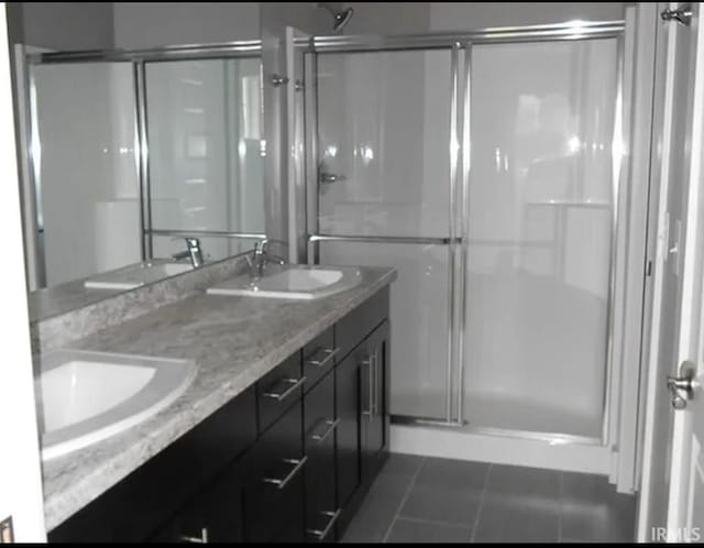 bathroom with tile patterned flooring, vanity, and walk in shower