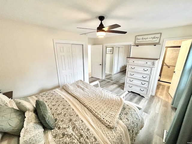 bedroom featuring hardwood / wood-style floors, two closets, and ceiling fan