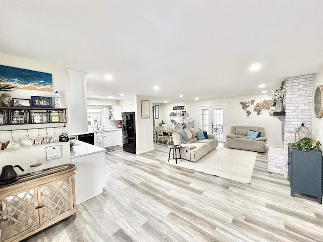 living room with sink, light hardwood / wood-style flooring, and french doors