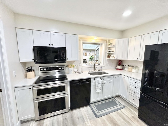 kitchen with white cabinetry, sink, and black appliances