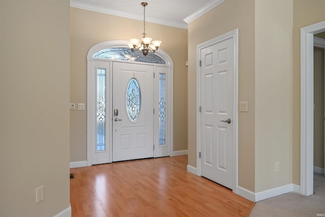 entrance foyer with ornamental molding, a chandelier, and light hardwood / wood-style floors