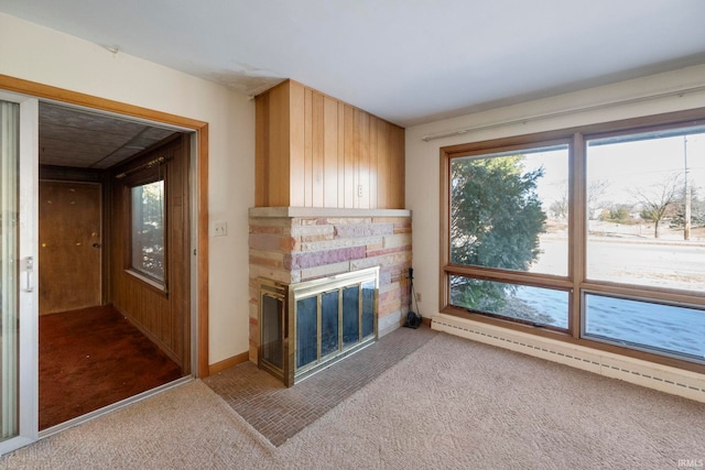 unfurnished living room featuring carpet flooring, a stone fireplace, and baseboard heating