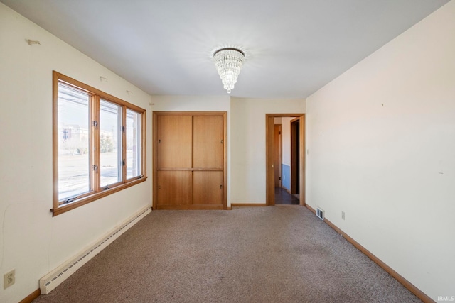 spare room featuring carpet, a chandelier, and baseboard heating