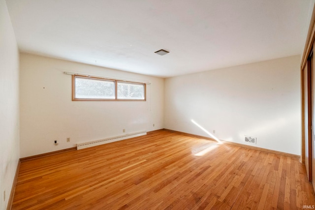 empty room featuring light wood-type flooring and baseboard heating