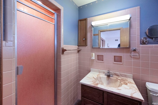 bathroom featuring vanity, toilet, and tile walls