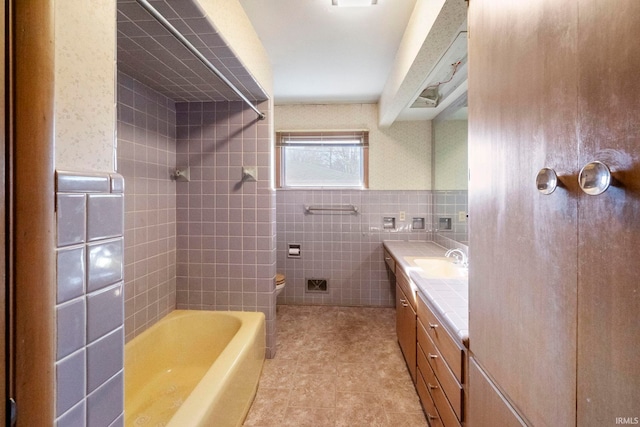 full bathroom featuring vanity, tiled shower / bath combo, toilet, and tile walls