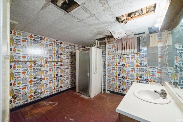 bathroom featuring brick wall, a shower with door, and vanity