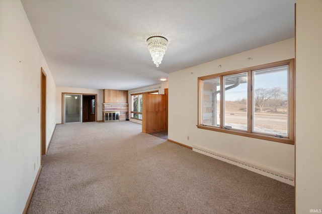 spare room with baseboard heating, light colored carpet, and an inviting chandelier