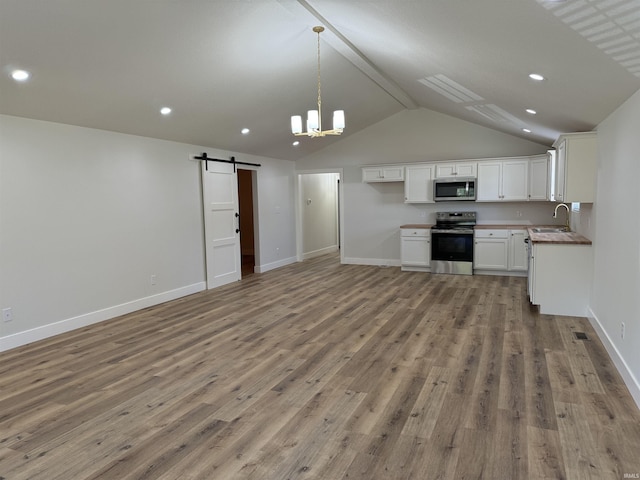 kitchen featuring sink, appliances with stainless steel finishes, white cabinets, a barn door, and light wood-type flooring