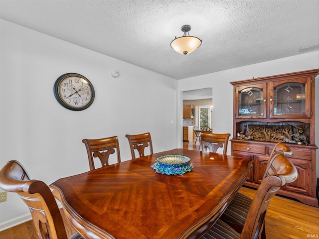 dining area with light hardwood / wood-style flooring and a textured ceiling