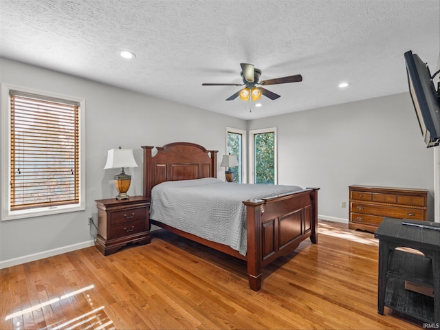 bedroom featuring ceiling fan, a textured ceiling, and light hardwood / wood-style floors