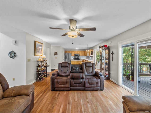 living room featuring ceiling fan, a textured ceiling, and light hardwood / wood-style floors