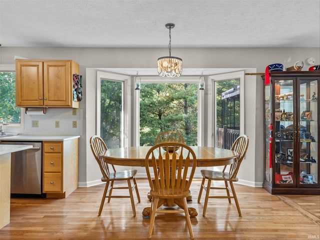 dining space featuring a healthy amount of sunlight, a chandelier, light hardwood / wood-style flooring, and a textured ceiling