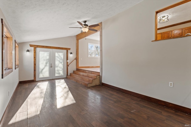 unfurnished living room featuring lofted ceiling, ceiling fan, dark wood-type flooring, a textured ceiling, and french doors