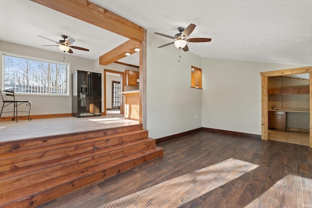 unfurnished living room featuring sink, dark hardwood / wood-style floors, vaulted ceiling with beams, and ceiling fan