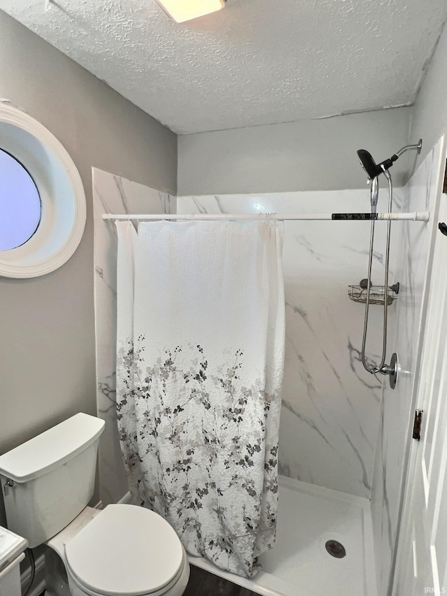 bathroom with a textured ceiling, toilet, and walk in shower