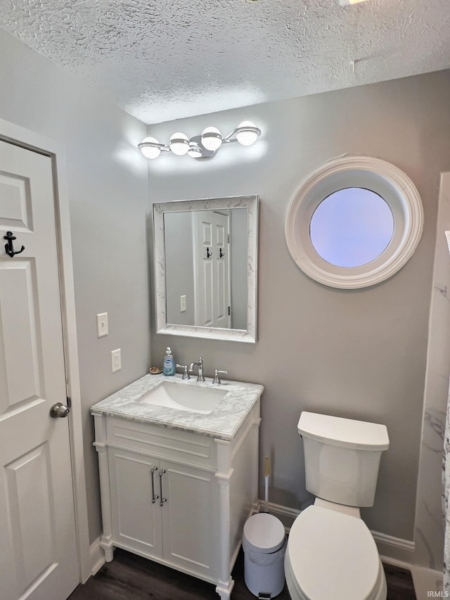 bathroom featuring vanity, toilet, hardwood / wood-style floors, and a textured ceiling