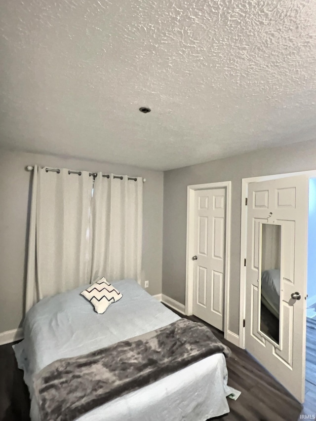 bedroom featuring dark wood-type flooring and a textured ceiling