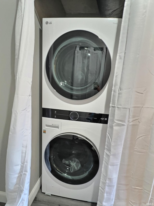 laundry room with hardwood / wood-style floors and stacked washing maching and dryer