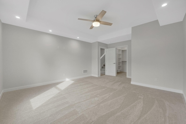 unfurnished bedroom with ceiling fan, a spacious closet, and light carpet