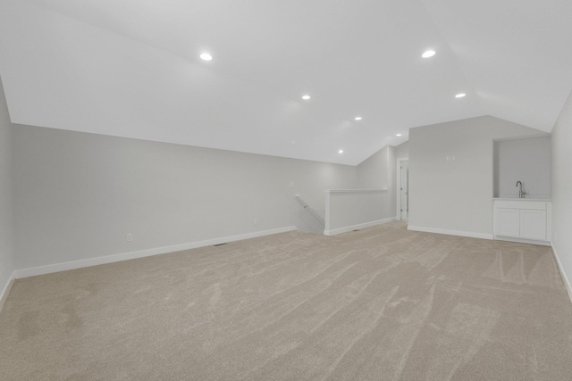 bonus room with light colored carpet, sink, and vaulted ceiling